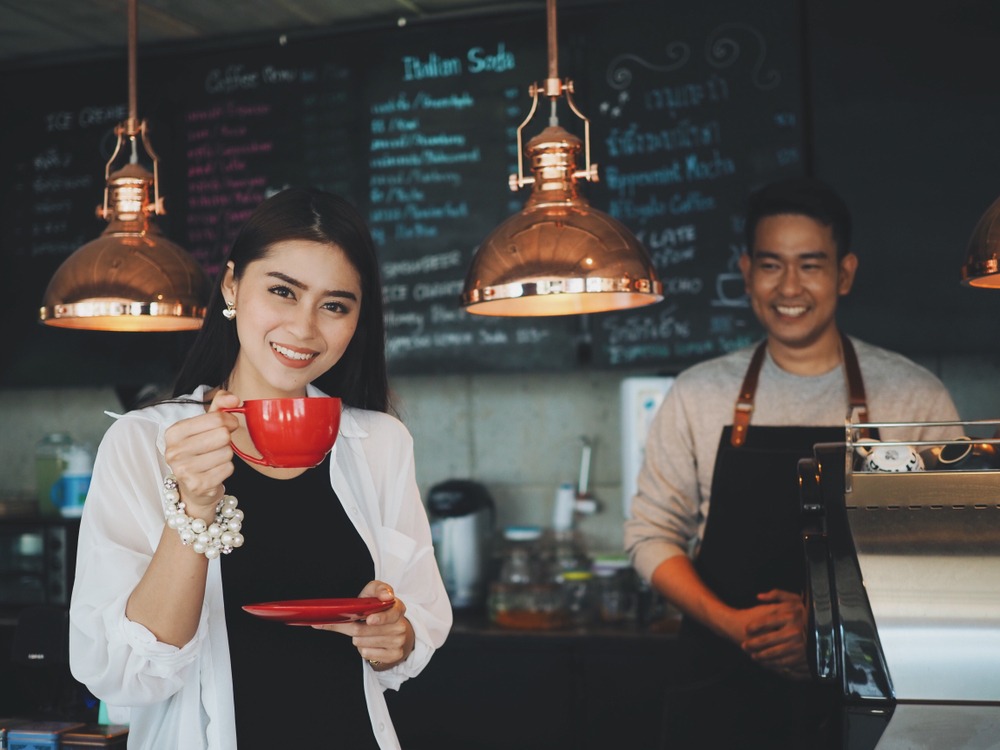 A customer enjoying coffee while the local owner serves from behind the counter